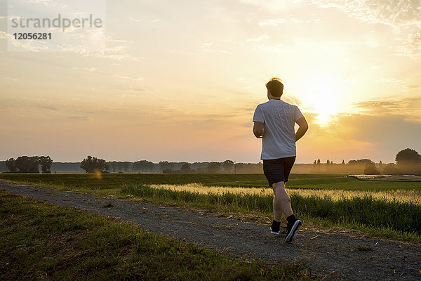 Mann läuft in ländlicher Landschaft bei Sonnenuntergang