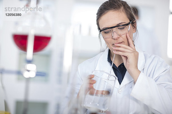 Wissenschaftlerin im Labor mit Becherglas und Pipette