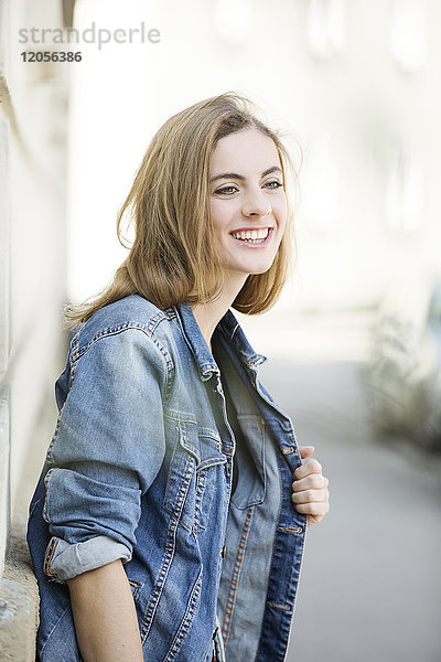 Porträt einer lächelnden jungen Frau vor der Hausfassade