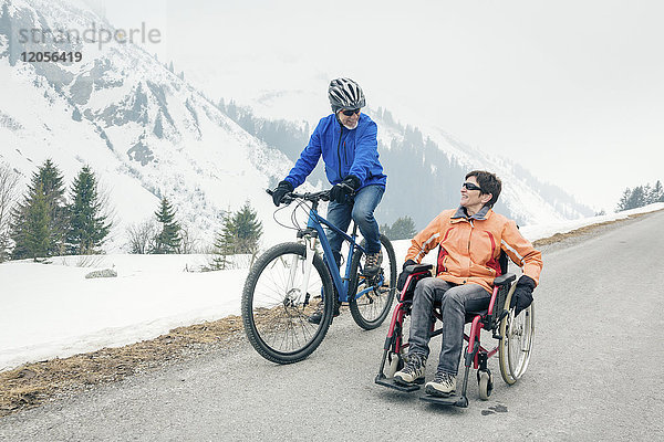 Österreich  Damuels  Seniorenpaar mit Fahrrad und Rollstuhl genießen einen Wintertag