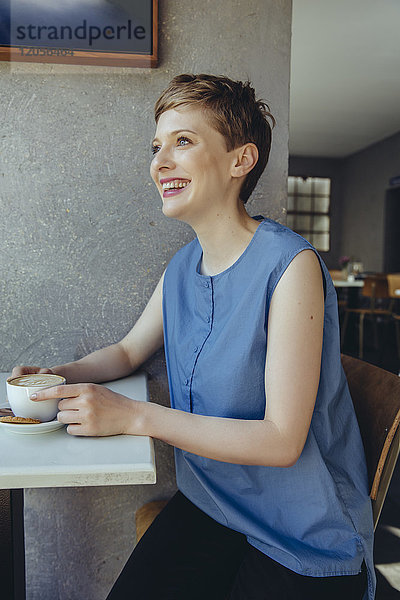 Glückliche Frau mit einer Tasse Kaffee im Café