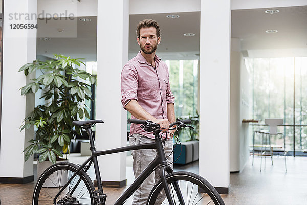 Porträt eines Mannes mit Fahrrad im Büro