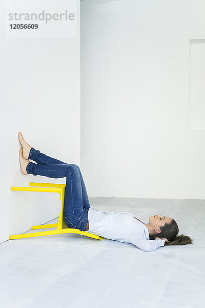 Frau auf dem Boden liegend mit einem gelben Stuhl