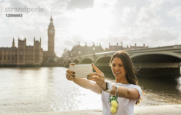 UK  London  schöne Frau  die einen Selfie in der Nähe der Westminster Bridge nimmt.