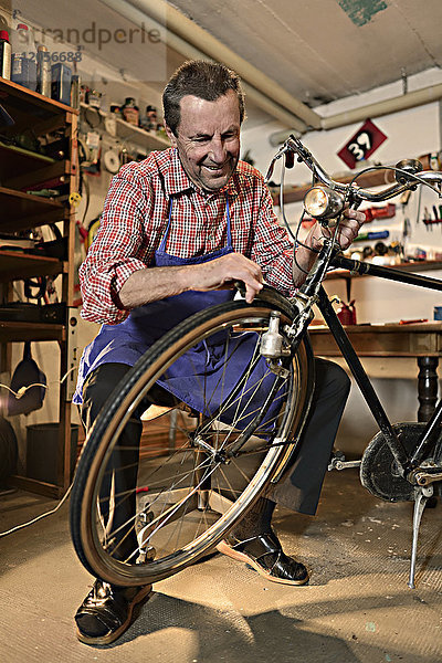 Älterer Mann repariert Fahrrad in seiner Werkstatt