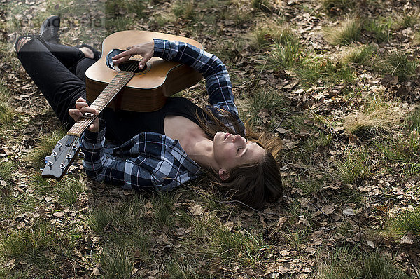 Frau auf der Wiese liegend  Gitarre spielend