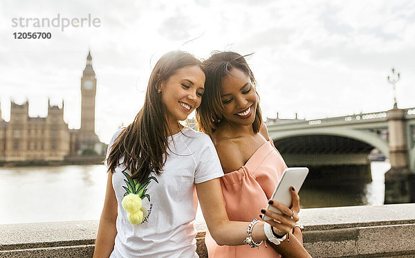 UK  London  zwei schöne Frauen  die einen Selfie in der Nähe der Westminster Bridge nehmen.