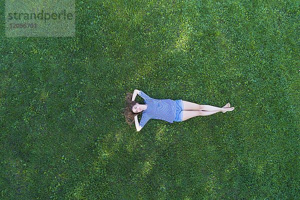 Junge Frau auf Gras liegend  tagträumend