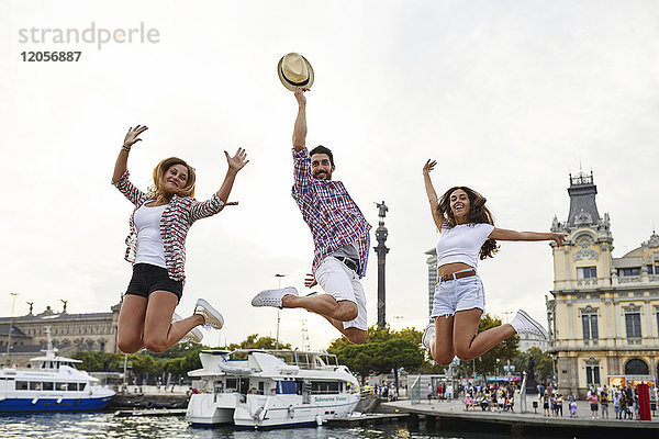 Spanien  Barcelona  drei Freunde beim Springen im Stadtzentrum am Meer