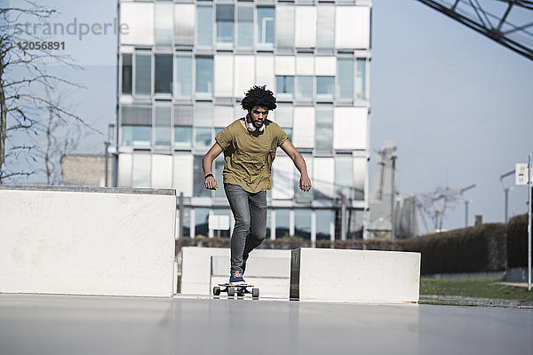 Junger Mann auf dem Longboard im Skatepark