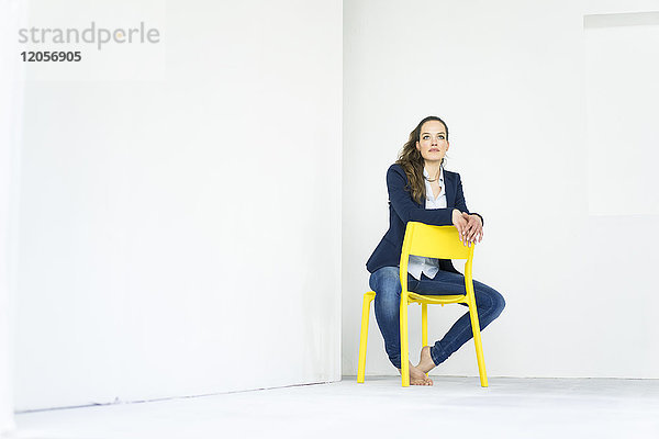 Geschäftsfrau auf einem gelben Stuhl sitzend  denkend