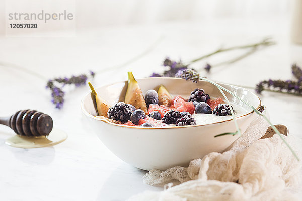 Schale aus griechischem Joghurt mit Feige  Wassermelone  gefrorenen Beeren und Lavendelhonig