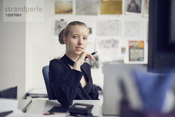 Porträt einer jungen Geschäftsfrau am Schreibtisch im Büro