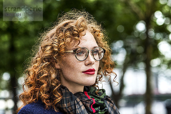 Porträt einer rothaarigen jungen Frau mit roten Lippen und Brille
