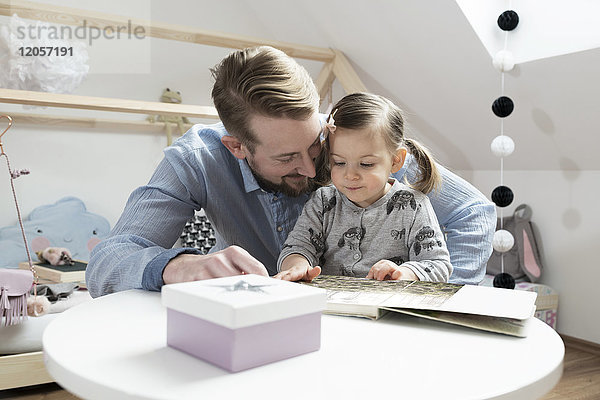 Vater und Tochter beim Betrachten des Fotoalbums in ihrem Kinderzimmer