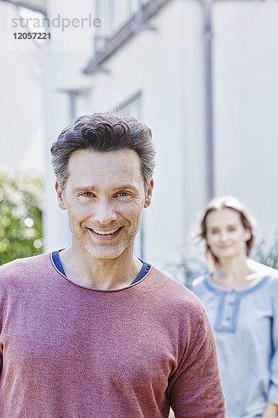Porträt des lächelnden Mannes mit Frau im Hintergrund