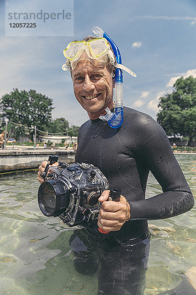 Porträt eines glücklichen Mannes mit Unterwasser-DSLR-Kameragehäuse im See