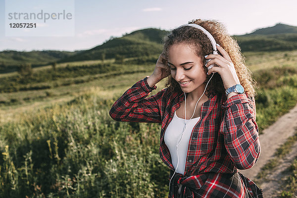 Teenagermädchen beim Musikhören mit Kopfhörern in der Natur