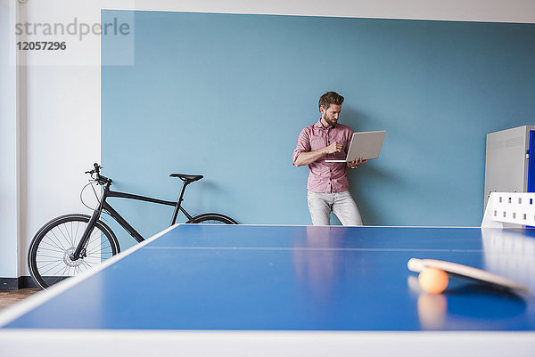 Mann mit Laptop im Pausenraum des modernen Büros