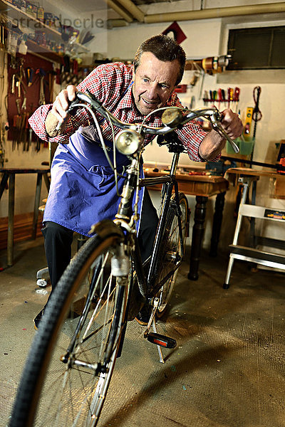 Älterer Mann beim Radfahren in seiner Werkstatt