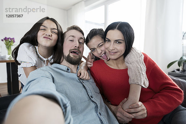 Eltern und Zwillingstöchter  die mit einem Selfie herumspielen.