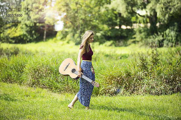 Junge Woan in der Natur mit Gitarre