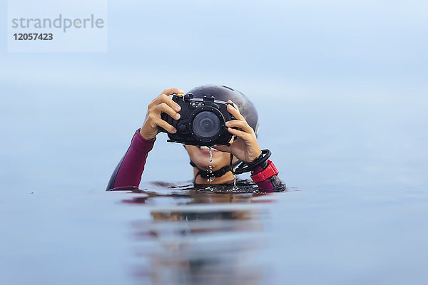 Lächelnde Frau mit Unterwasserkamera im Meer