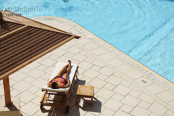 Frau entspannt in der Sonnenliege am Pool