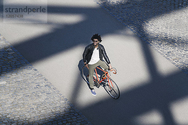 Erhöhter Blick auf lächelnden Mann mit Sonnenbrille auf dem Fahrrad