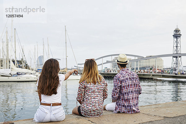 Spanien  Barcelona  drei Touristen  die auf einem Pier in der Stadt sitzen.