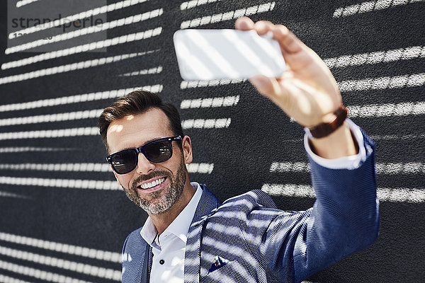 Geschäftsmann nimmt Selfie mit Smartphone mit ins Freie