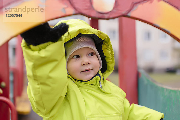 Kleinkind mit Regenjacke auf dem Spielplatz