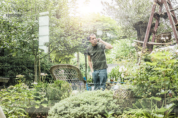 Mann spricht auf dem Smartphone im Garten