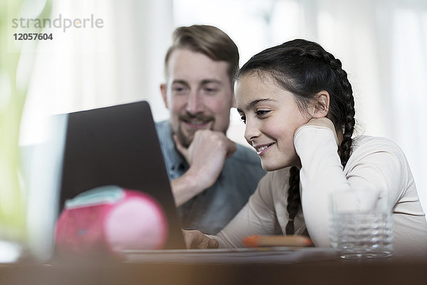 Vater und Tochter schauen gemeinsam auf den Laptop