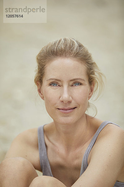Porträt einer lächelnden blonden Frau am Strand