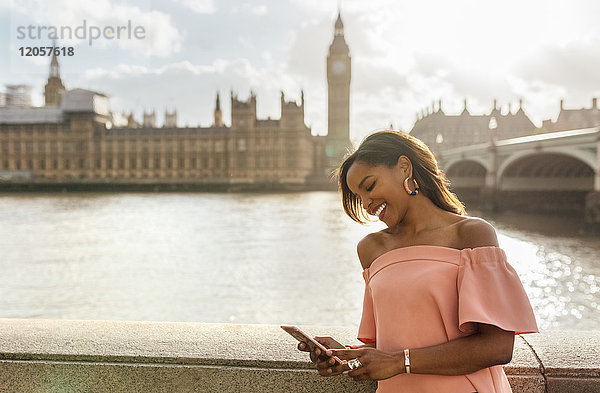 UK  London  Frau  die Nachrichten mit ihrem Smartphone in der Nähe der Westminster Bridge sendet.