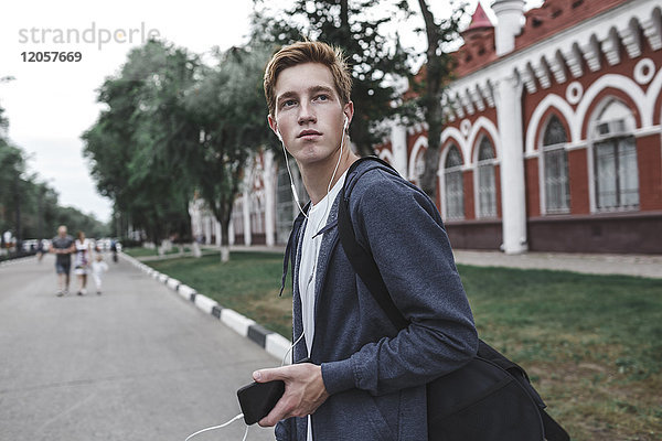 Junger Mann mit Handy und Kopfhörer in der Stadt