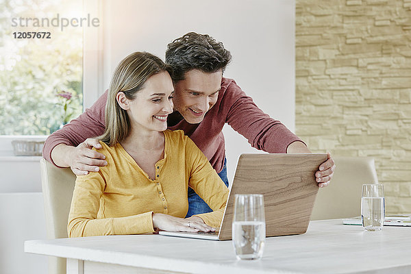 Glückliches Paar zu Hause mit dem Laptop