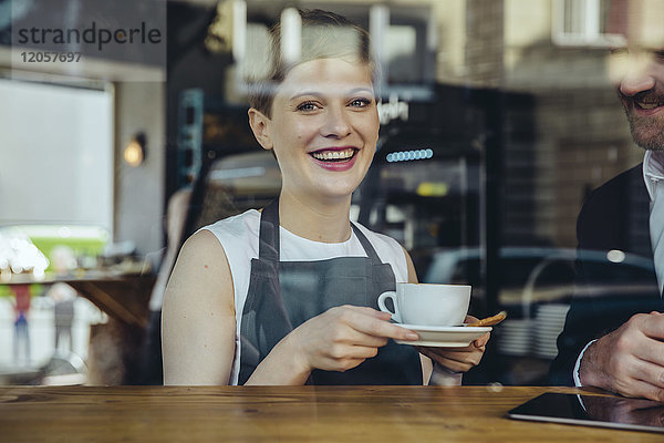 Lächelnde Kellnerin serviert dem Kunden Kaffee im Cafe
