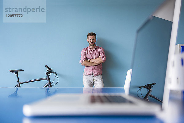 Portrait von lächelndem Mann und Laptop im Pausenraum des modernen Büros
