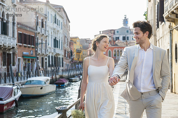 Italien  Venedig  glückliches Brautpaar  das in der Morgendämmerung Hand in Hand geht.