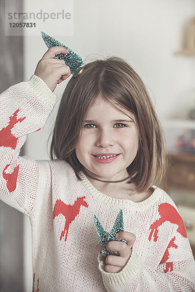 Porträt eines lächelnden Mädchens mit Miniatur-Weihnachtsbäumen