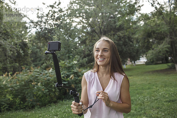 Lächelnde junge Frau beim Fotografieren auf einer Wiese