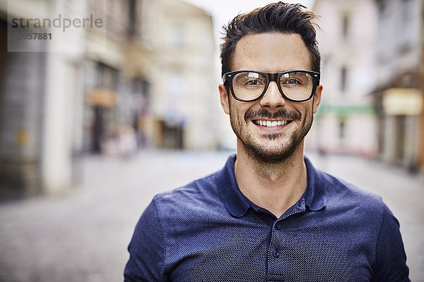Porträt eines lächelnden Mannes mit Brille in der Stadt