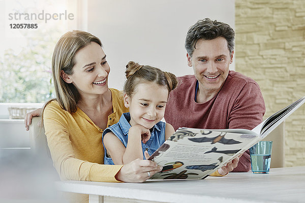 Glückliche Familie zu Hause beim Betrachten des Bilderbuches