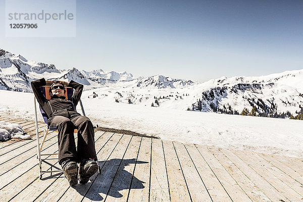 Österreich  Damuels  Frau entspannt im Liegestuhl auf dem Sonnendeck in Winterlandschaft