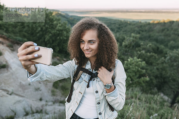 Lächelndes Teenagermädchen nimmt Selfie in der Natur auf