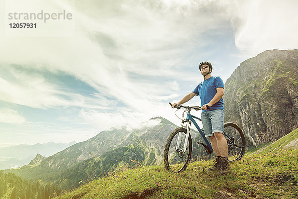 Deutschland  Bayern  Pfronten  Mann mit Mountainbike auf der Alm bei Aggenstein