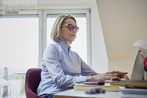 Reife Frau zu Hause mit Laptop am Schreibtisch