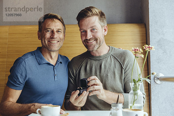 Portrait eines schwulen Paares mit Ehering im Café